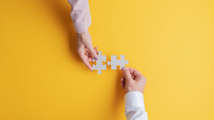 Two hands joining jigsaw pieces