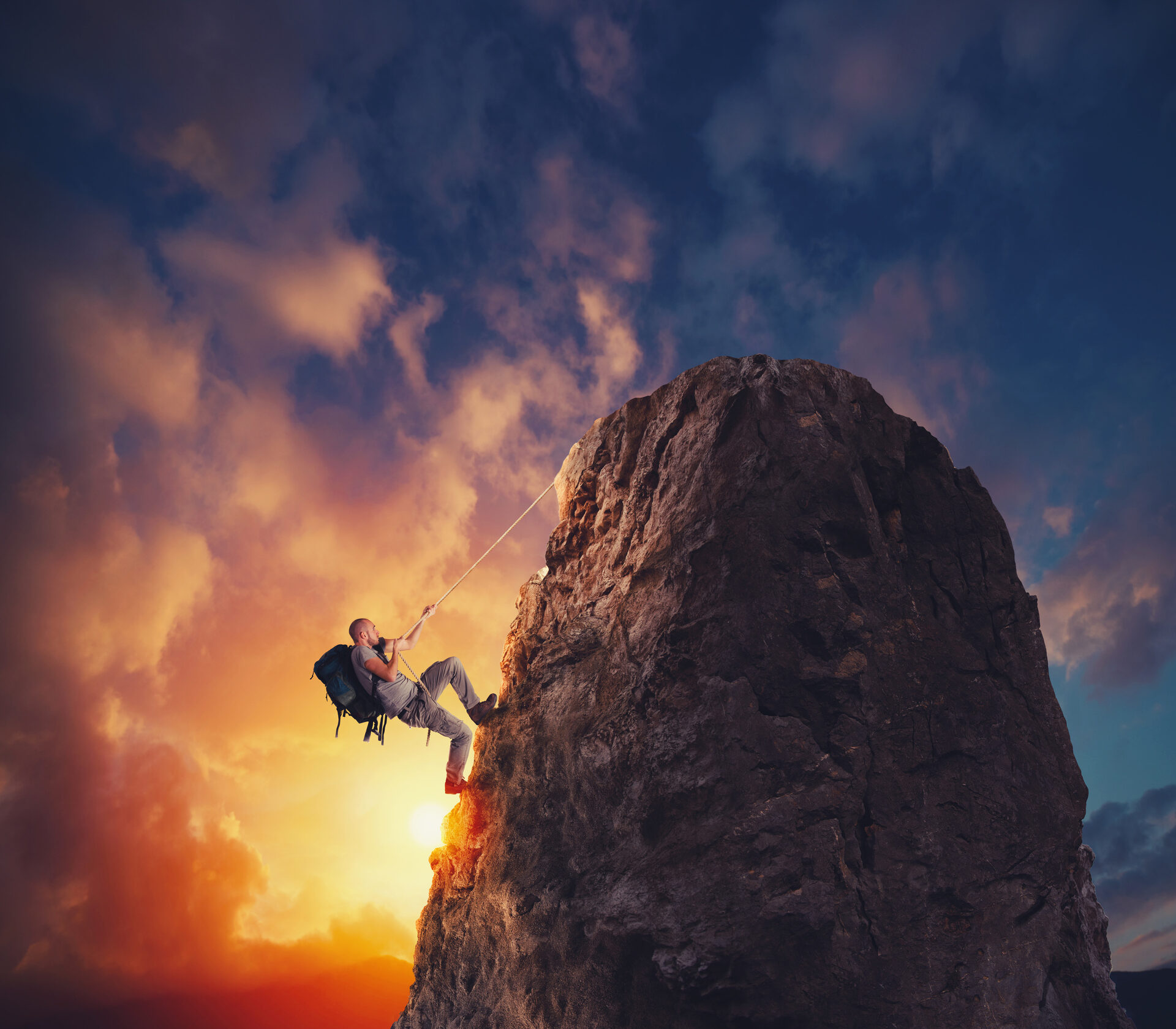 A climber on a rock face at sunset